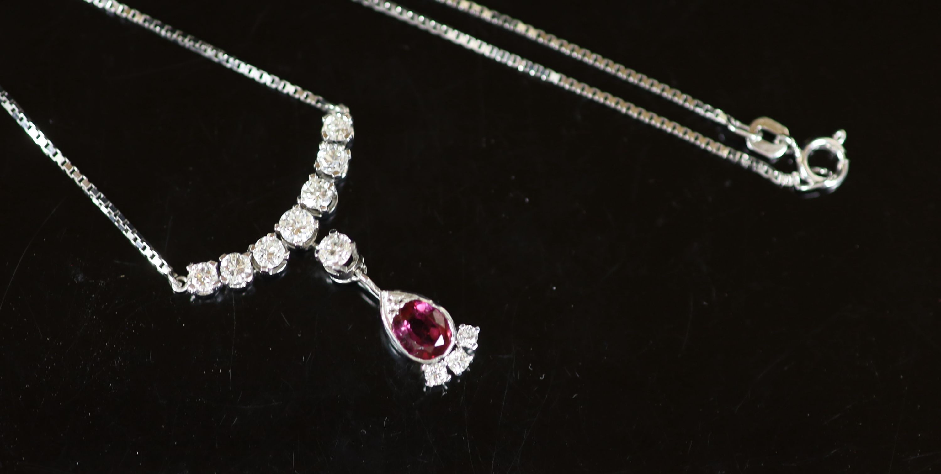 A modern Italian 18ct white gold, single stone oval cut ruby and eleven stone diamond set drop pendant necklace